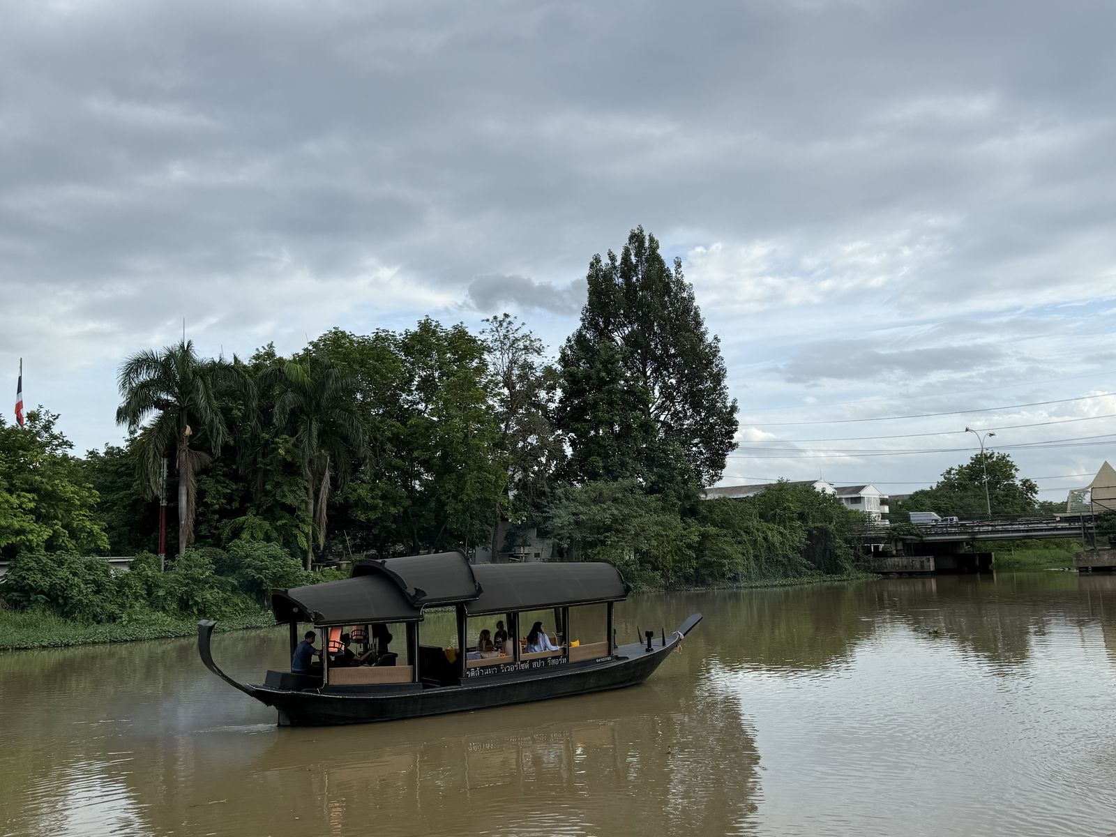 Traditional wooden boat cruising the Ping River in Chiang Mai