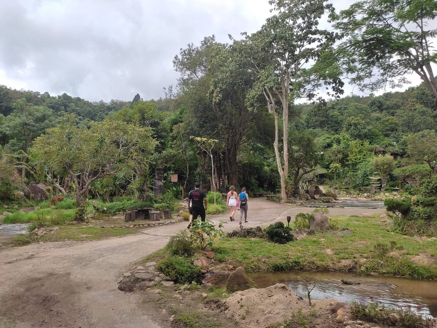Travelers walking a green village path outside Chiang Mai